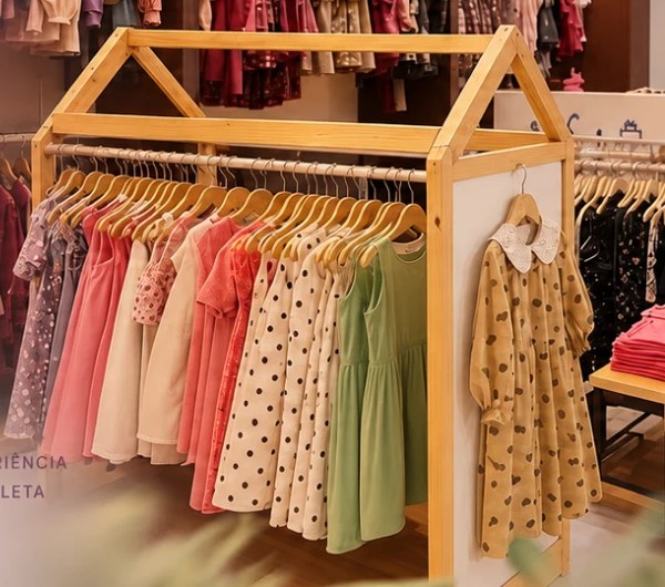 Arara de madeira em forma de casinha com vestidos rosa, poá e verde
