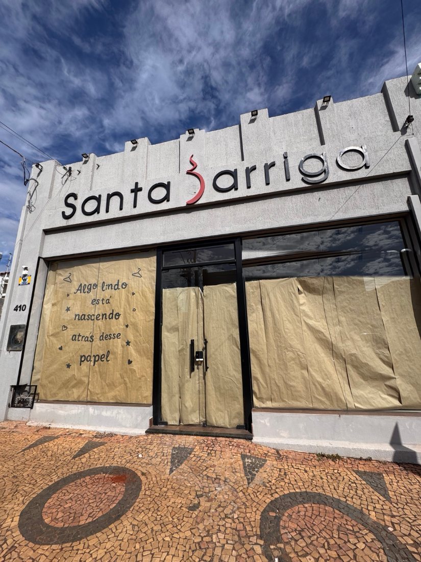 Fachada da Santa Barriga com as vitrines cobertas de papel pardo e a frase: algo lindo está nascendo atrás desse papel