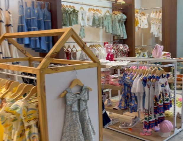 Salão da loja com araras de casinha e vestidos coloridos