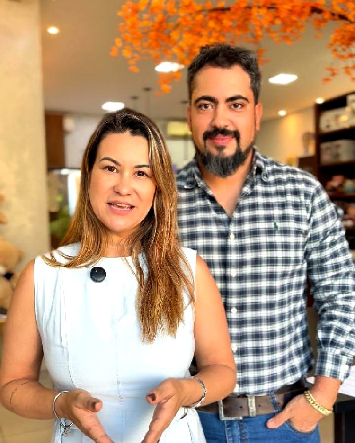 Nani e Manoel dentro da loja Santa Barriga, sob a árvore de folhas laranja